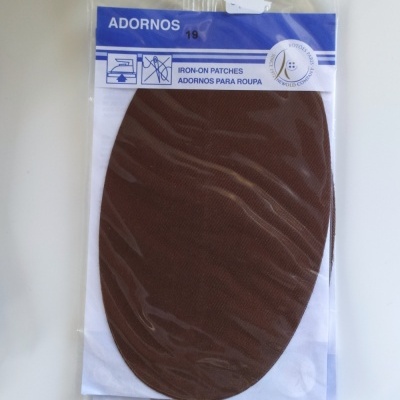 Adorno oval castanho de tecido para roupa em embalagem transparente com etiqueta azul e branca.