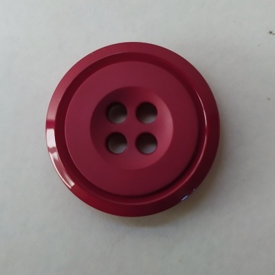 Botão vermelho vinho redondo com quatro orifícios em superfície branca