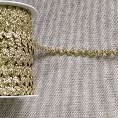 Rolo de fita ondulada dourada com brilho sobre tecido cinzento