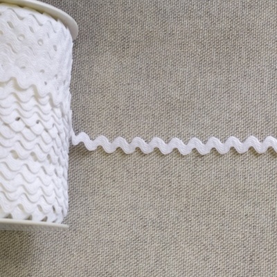 Rolo de fita ondulada branca em tecido sobre fundo cinzento com texto 'Branco'