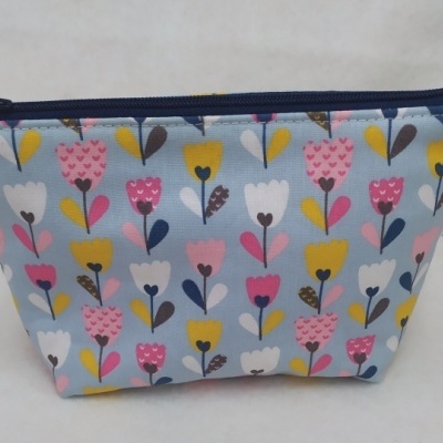 Bolsa pequena com padrão floral em fundo azul e fecho azul escuro