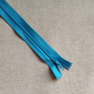 Fecho éclair azul sobre tecido bege claro com texto Cor 606