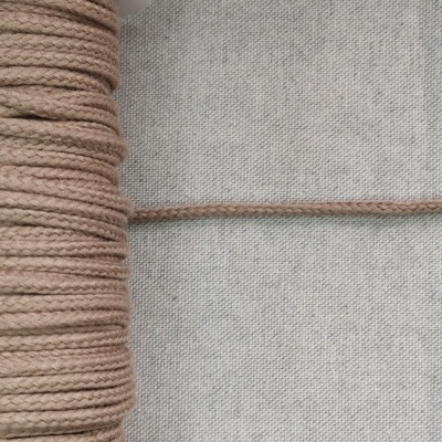 Rolo de cordão castanho sobre tecido cinza claro com texto