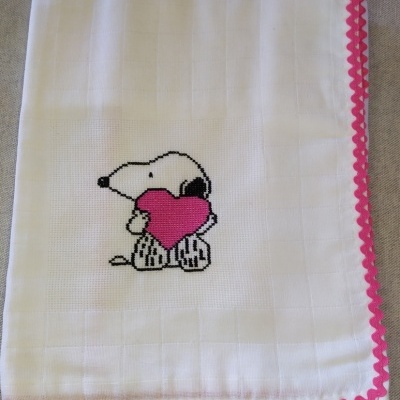 Pano branco com bordado do Snoopy segurando um coração rosa e borda decorada rosa
