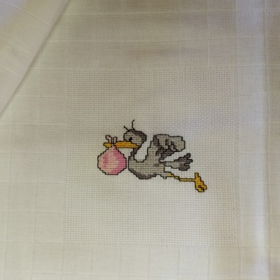 Tecido branco com bordado de cegonha cinzenta a voar com um saco rosa