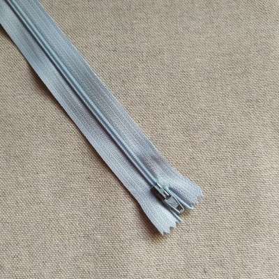 Fecho éclair cinza claro com texto Cor 583 em fundo de tecido bege