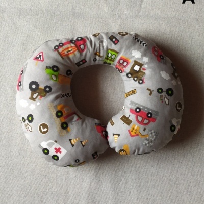 Almofada em formato de U com padrão de veículos coloridos em tecido cinza.