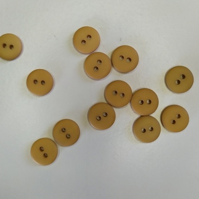 Botões castanhos claros circulares com dois orifícios, sobre superfície branca
