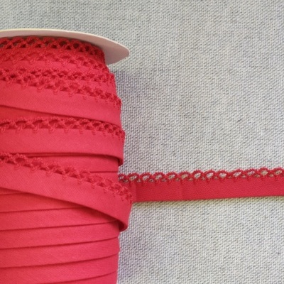 Rolo de fita vermelha com bordado triangular sobre superfície cinzenta, texto 'Vermelho' acima