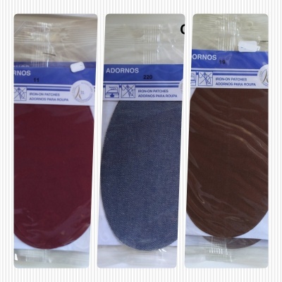 Três remendos para roupa em pacotes plásticos, cores vermelho, cinza e castanho.