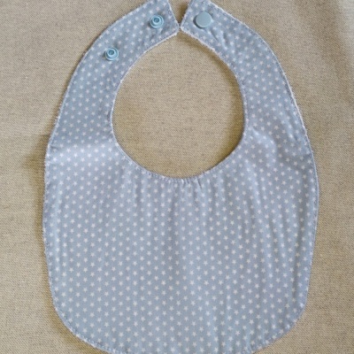 Babete para bebé azul claro com estrelas brancas e fechos de pressão azuis