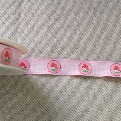 Fita rosa com padrão de cogumelos vermelhos em tecido sobre fundo cinzento