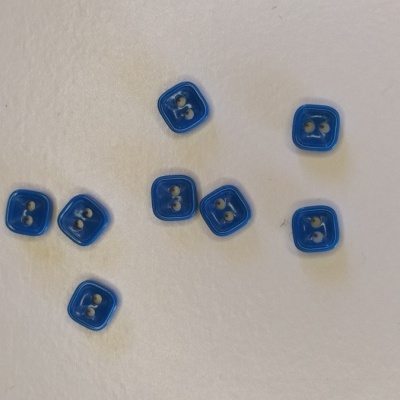 Botões quadrados azuis de plástico com dois buracos sobre superfície branca