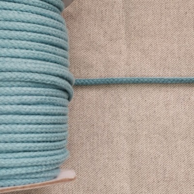 Rolo de cordão têxtil azul claro em suporte de cartão sobre tecido bege, com texto 'Azul Claro'.