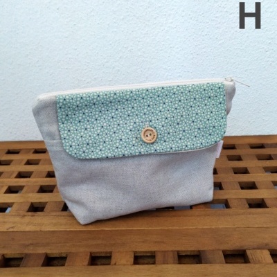 Bolsa pequena de tecido cinzento e azul com padrão de flores brancas e botão de madeira