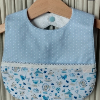 Babete azul claro com pequenos pontos e padrão animal infantil