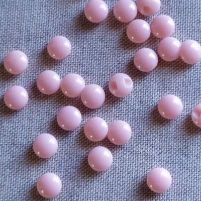 Contas redondas cor-de-rosa sobre tecido cinzento com texto 'Rosa'