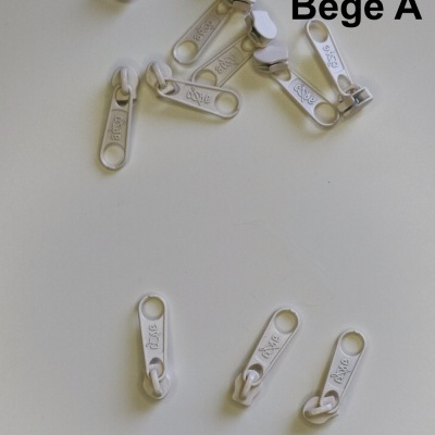 Cursoras de fecho éclair metálicas bege claro sobre fundo branco com texto 'Bege A'