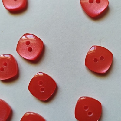 Botões quadrados vermelhos com dois furos sobre superfície branca