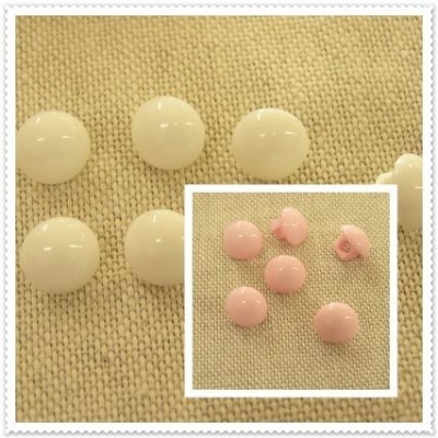 Botões redondos em resina branca e rosa sobre tecido bege
