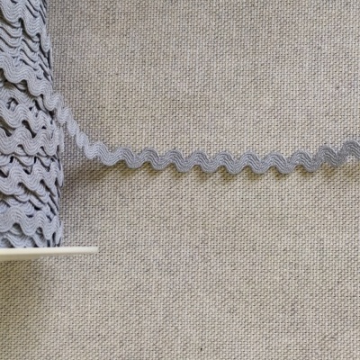 Rolo de fita ondulada cinza sobre tecido cinza claro com texto 'Cinza'.