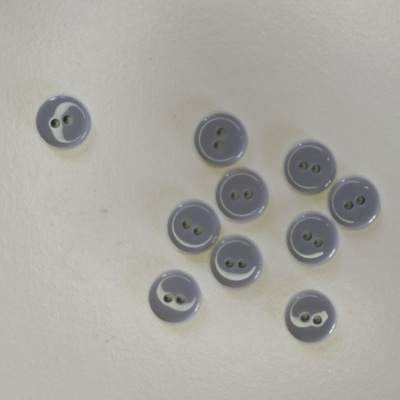 Dez botões cinzentos redondos com dois buracos sobre uma superfície branca