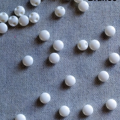 Contas brancas redondas sobre tecido cinzento com texto 'Branco'