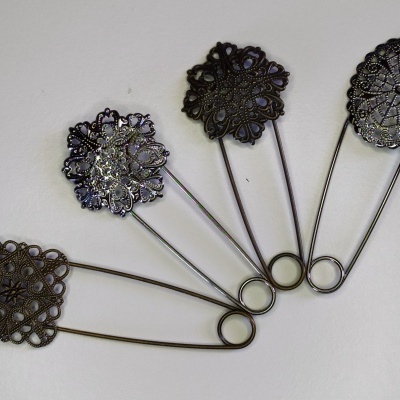 Alfinetes de segurança decorativos em metal dourado envelhecido, com diferentes padrões de filigrana.
