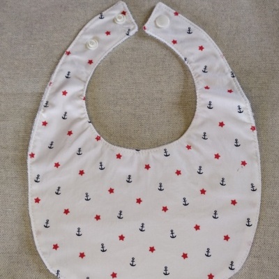 Babete branco com padrão de âncoras azuis e estrelas vermelhas com fecho de pressão