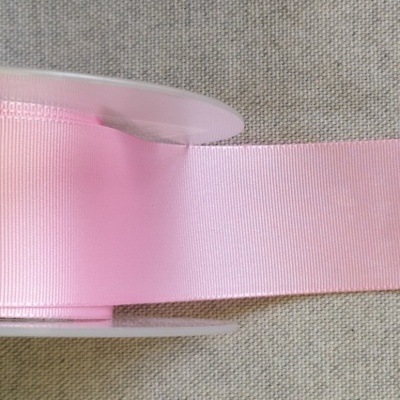 Rolo de fita cor-de-rosa claro em superfície de tecido cinzento