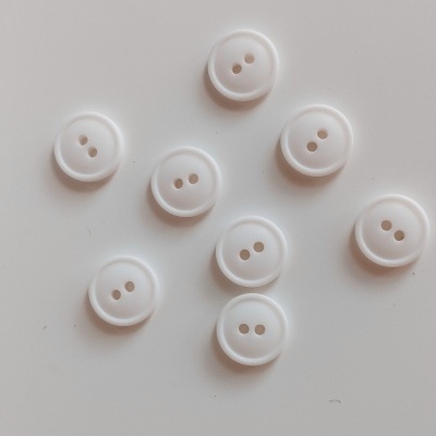 Botões brancos redondos com dois furos sobre superfície branca