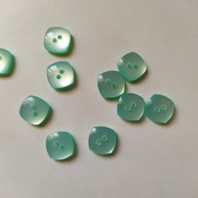 Botões quadrados verde água com dois furos sobre fundo branco