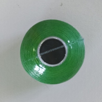 rolo de linha verde com núcleo cinza em fundo branco