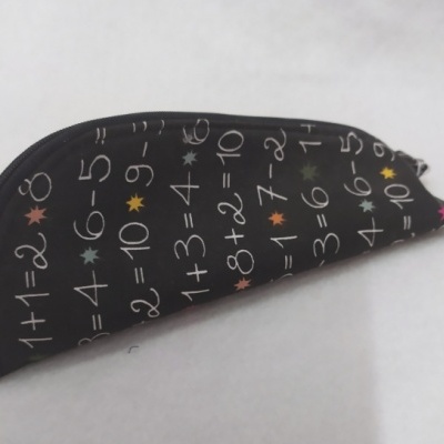 Estojo escolar preto com estampado de operações matemáticas e estrelas coloridas