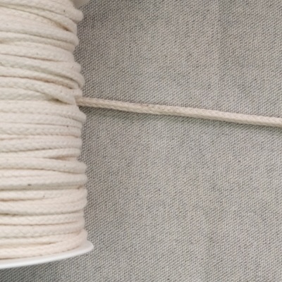 Rolo de cordão grosso de cor cru sobre fundo cinzento