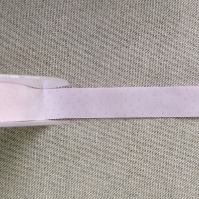 Fita cor-de-rosa clara com pintas sobre fundo de tecido cinzento