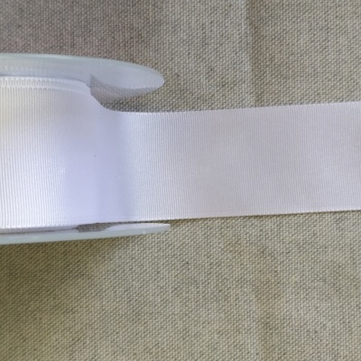 Rolo de fita branca sobre tecido cinzento com texto 'Branco'