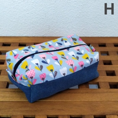 Necessaire retangular com padrão de flores coloridas e base azul escuro sobre superfície de madeira