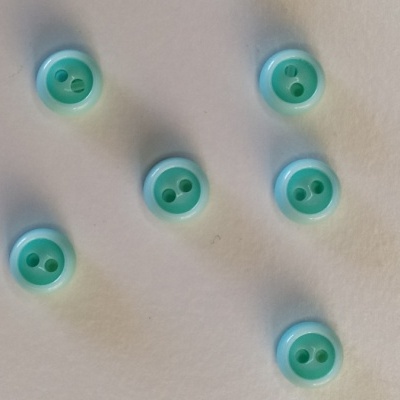 Seis botões redondos verde claro com dois orifícios sobre fundo branco