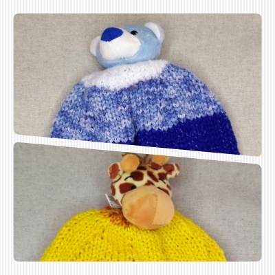 Gorros de malha azul com urso e amarelo com girafa sobre fundo cinzento