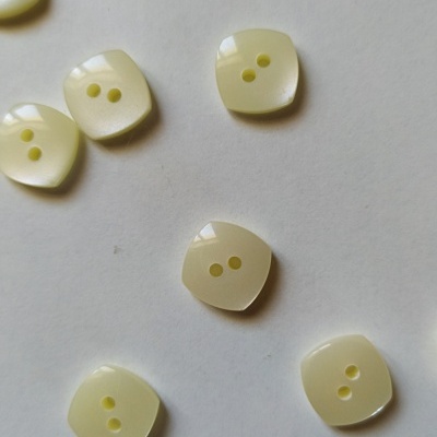 Botões quadrados amarelo claro com dois buracos, sobre fundo branco