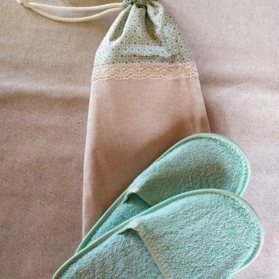 Chinelos de banho verdes com bolsa de tecido bege e renda