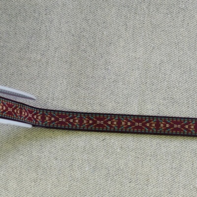 Fita têxtil estreita com padrão geométrico colorido sobre fundo bege.