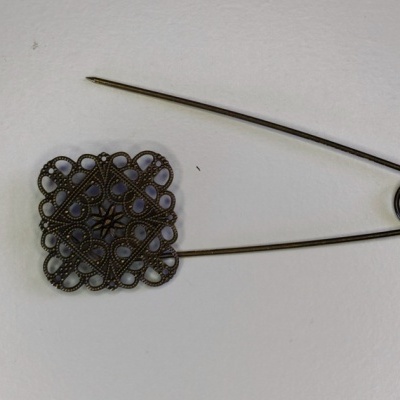 Alfinete de metal com cabeça decorativa quadrada em fundo branco