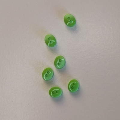 Seis contas verdes ovais com dois furos, sobre fundo branco.