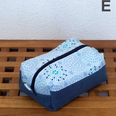 Necessaire azul e branca com fecho de correr sobre superfície de madeira.