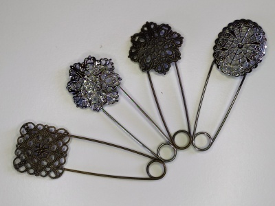 Alfinetes de segurança decorativos em metal dourado envelhecido, com diferentes padrões de filigrana.
