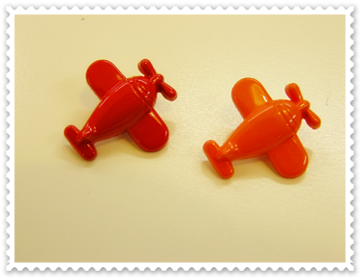 Dois brinquedos pequenos de avião em plástico vermelho e laranja