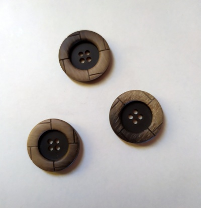 Três botões redondos castanhos com centro preto e quatro furos