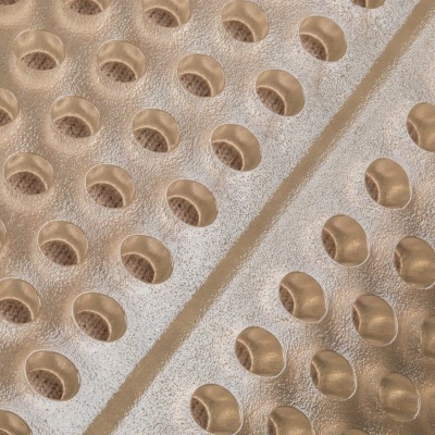 Superfície metálica dourada com orifícios arredondados em padrão repetido